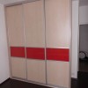 velká vestavěná skříň s vícedílnými posuvnými dveřmi v dekoru dřeva s červeným pruhem