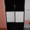 Volně stojící černá skříň s posuvnými dveřmi s bílými prvky