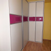 bílá rohová vestavěná skříň s růžovým lesklým pruhem na dveřích