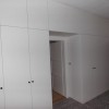 vícedílná velká bílá vestavěná skříň v délce stěny s výklenkem pro dveře