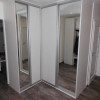 Bílá volně stojící skříň se zrcadly v rohu místnosti